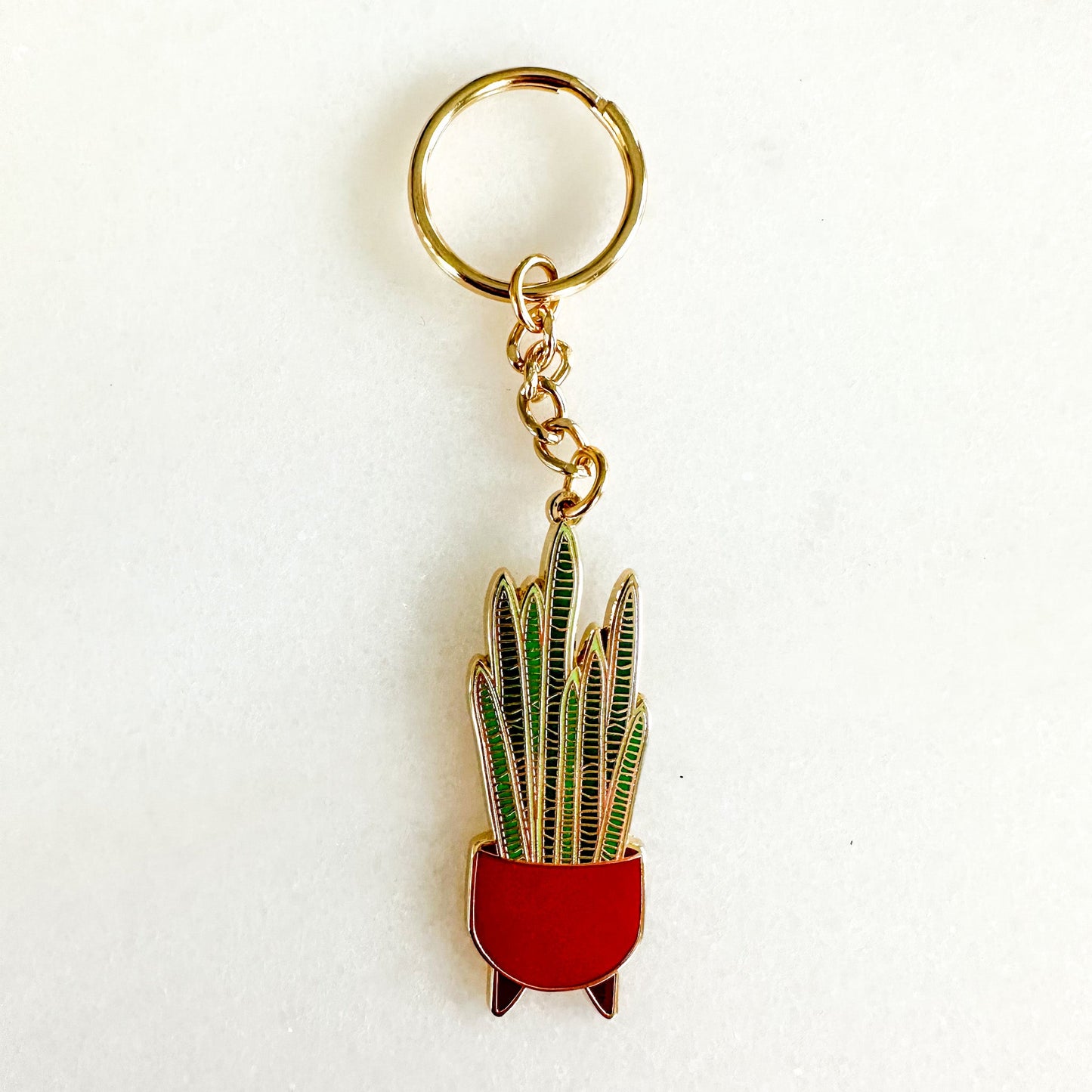 A gold keychain with a snake plant charm